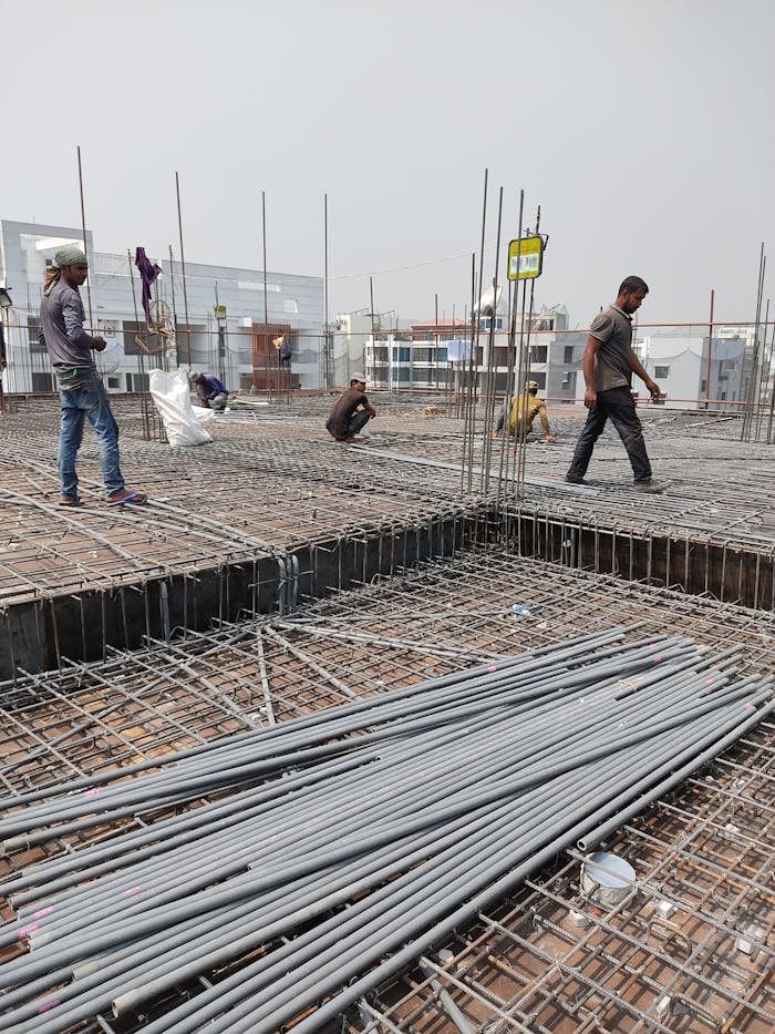 gallery-3 Workers engaged in construction on a building site, laying metal frameworks.