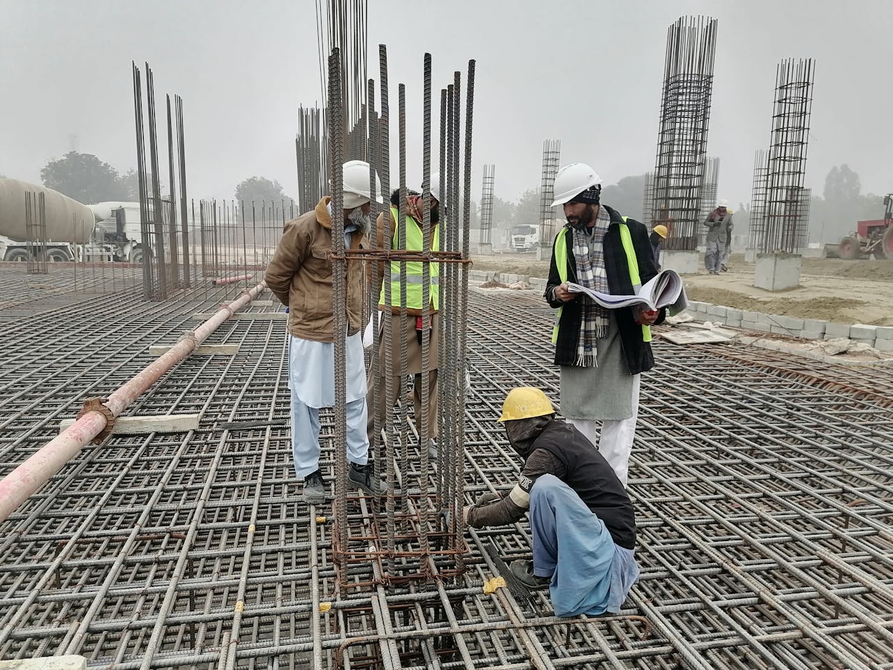 gallery-5 Construction workers and engineers at a site in Bahāwalnagar, Punjab, Pakistan, inspecting metal framework.