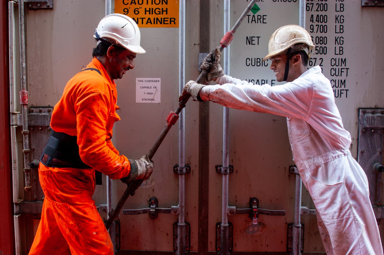 gallery-2 Two dockworkers securing a container on a ship, emphasizing teamwork and safety.