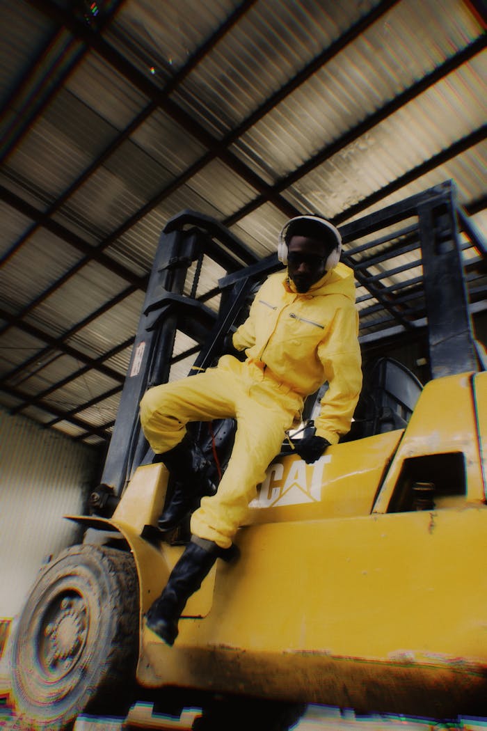 gallery-4 A worker in a bright yellow outfit operates a forklift inside a warehouse, showcasing modern industrial activity.